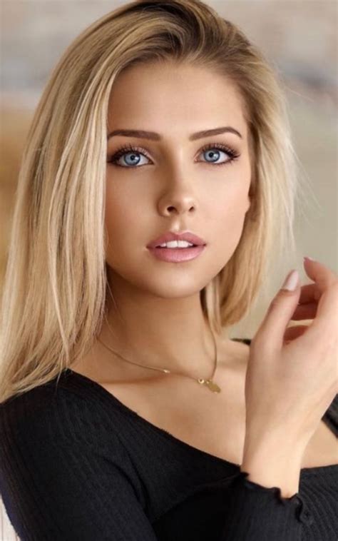 A Woman With Blonde Hair And Blue Eyes Posing For A Photo In A Black Top