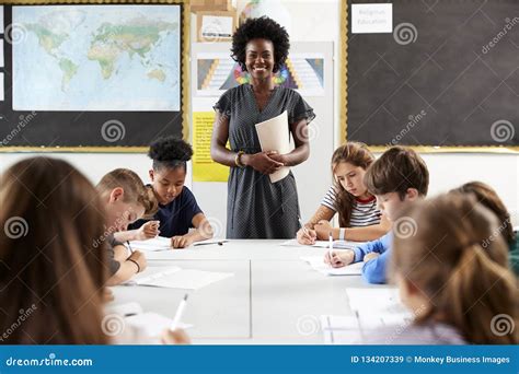 Portrait Of Female High School Teacher Standing By Table With Students