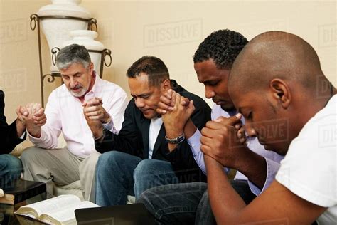 A Group Of Men Praying Together With An Open Bible Stock Photo Dissolve