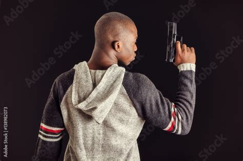 Young Handsome Black Man Holding A Hand Gun On Dark Background In
