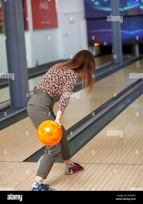 A Woman Throws A Ball Into A Bowling Alley Paths With Balls And Pins