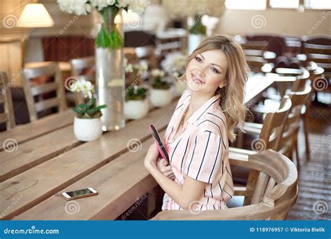 Young Attractive Woman Freelancer Sitting At The Table With Notepad And