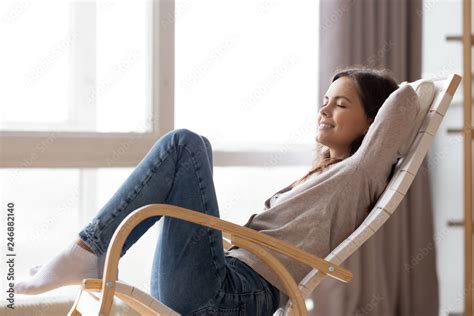 Relaxed Calm Young Woman Lounging Sitting In Comfortable Wooden Rocking Chair Breathing Fresh