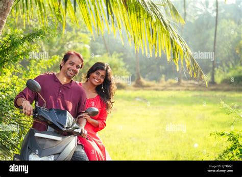 Happy Indian Married Couple Riding On Motorbike Adventure In Tropical Jungle In Goa India