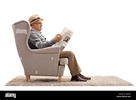Mature Man Sitting In An Armchair And Reading A Newspaper Isolated On