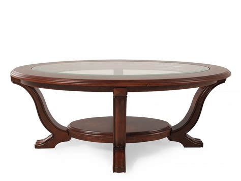 A glass table top over a graceful brown y, braced with white. Tempered Glass-Insert Oval Traditional Cocktail Table in Cherry | Mathis Brothers Furniture