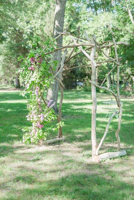 A Wooden Arbor With Vines And Flowers Growing On It In The Middle Of A Park
