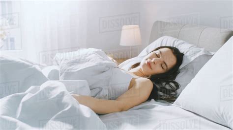 Attractive Brunette Cozily Sleeps In Her Bed While Early Morning Sunrays Illuminate Her Warm