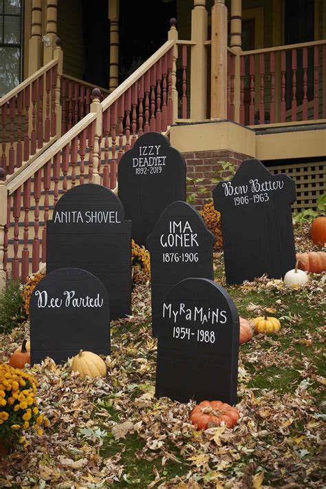 Several Headstones In Front Of A House With Fall Leaves On The Ground