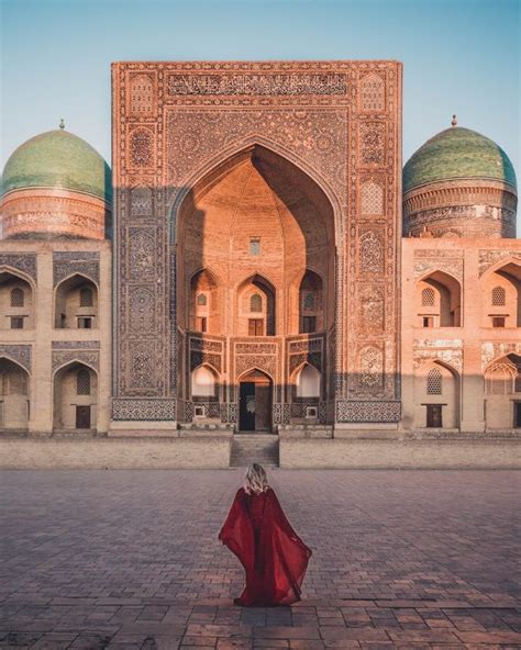 A Woman In A Red Dress Is Sitting On The Ground Near An Ornate Building With Arches And Domes