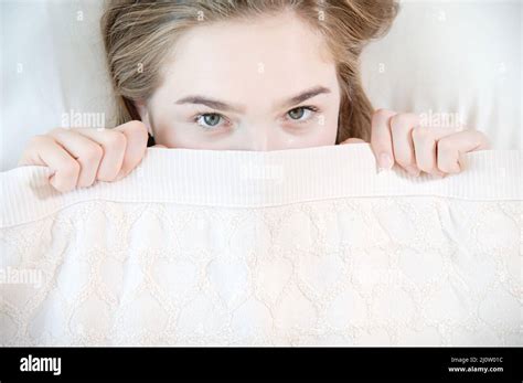 A Young Attractive Woman Peeks Out From Under The Blankets Hiding