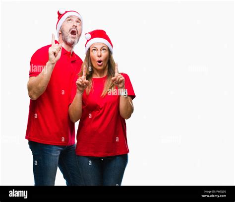middle age hispanic couple wearing christmas hat over isolated background amazed and surprised