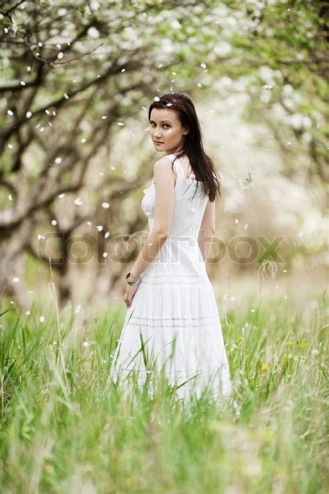 Portrait Of Beautiful Young Woman In White Dress Walking In Park
