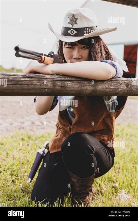 Portrait Of A Beautiful Chinese Female Cowgirl Shooting With A Weapon