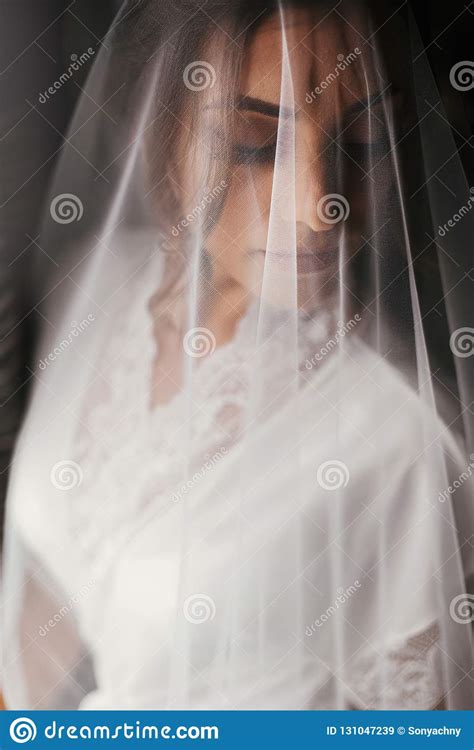 Gorgeous Beautiful Bride In Silk Robe Under Veil Posing At Window In