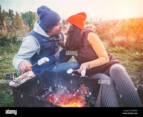 Happy Couple Kissing And Roasting Marshmallows On Campfire On Nature
