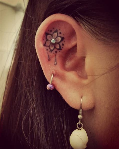 A Woman S Ear Has A Flower Tattoo On It