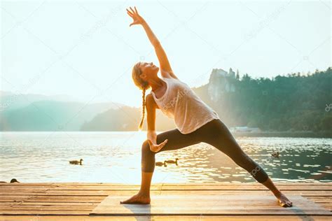 Woman Practicing Yoga By Lake — Stock Photo © Microgen 115158588