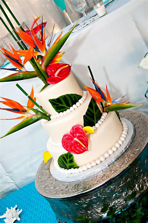 A Three Tiered Cake Decorated With Flowers And Birds Of Paradise On A