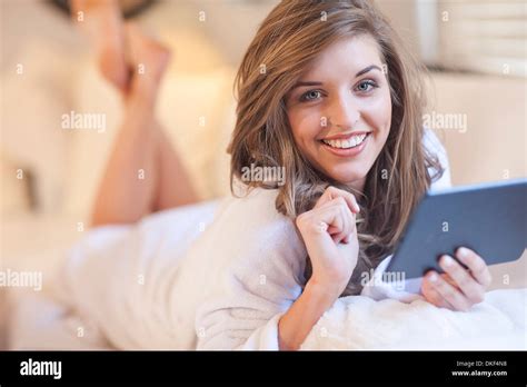 Portrait Of Young Woman Lying On Bed With Digital Tablet Stock Photo