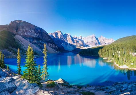 A Lake Surrounded By Mountains And Trees With Blue Water In The