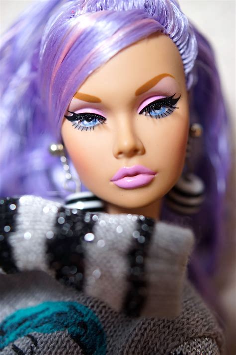 A Close Up Of A Doll With Purple Hair And Bright Blue Eyeshadow Wearing A Sweater