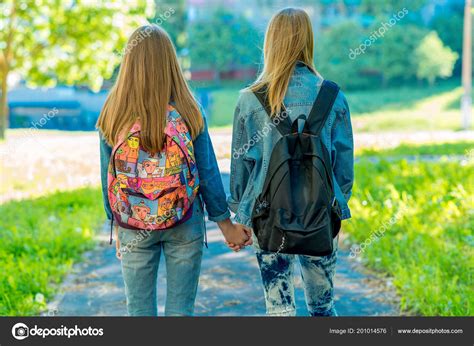 Two Girl Friends Schoolgirl Summer In Nature Girls Hold Each Others Hands Back View Returns