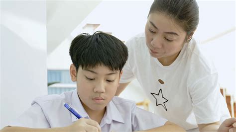 slow motion of asian mother helping her son doing homework on white table serious asian mother