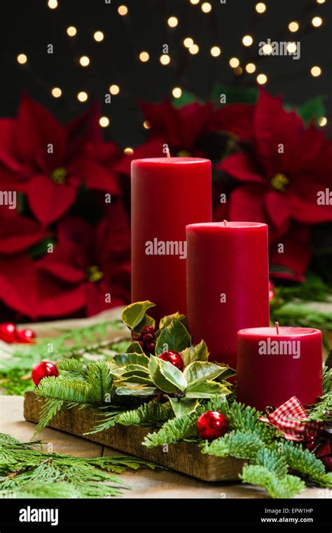 Red Candle Centerpiece With Poinsetias And Greens And Holly Stock Photo