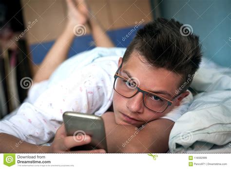 Tiener Die In Bed Liggen En Cellphone Gebruiken Stock Afbeelding