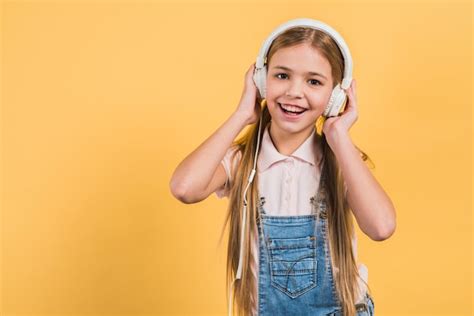 Retrato de uma menina feliz ouvindo música no fone de ouvido contra o