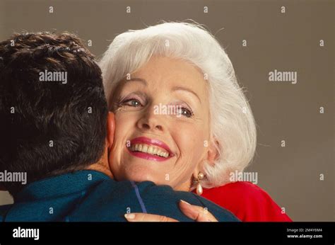 Older Gray Haired Caucasian Woman Hugging A Young Man She Is All Smiles And He Is Photographed