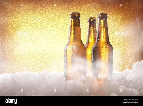 Three Full Beer Bottles On Crushed Ice And Golden Background