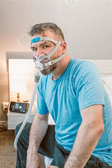 unhappy shocked man with chronic breathing issues surprised by using cpap machine sitting on the