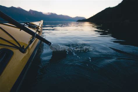 Kayaking Alone On Calm Water With Mountains In The Background While