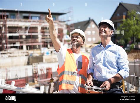 Smiling Construction Worker Talking To Man On Construction Site Stock