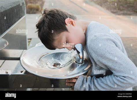 Thirsty Boy Drinking Water From Fountain At Park Stock Photo Alamy