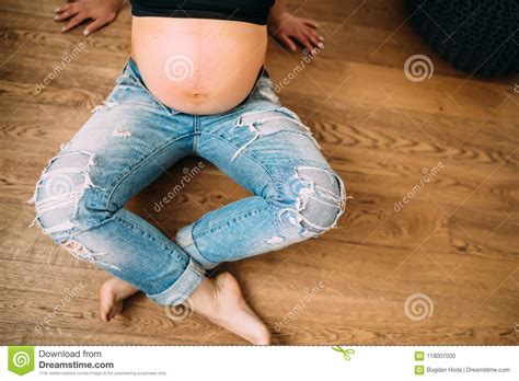 Close Up Details Of Baby Bump Pregnant Woman Sitting On Hardwood