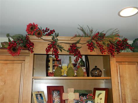 Stick trees and bottle brush christmas trees round out the charming christmas kitchen style. Decorating Above Kitchen Cabinets, garland - JOYFUL DAISY