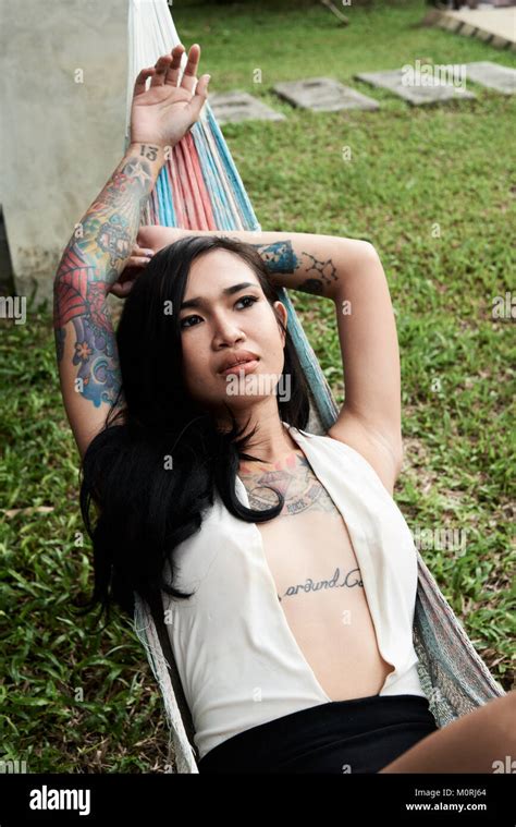 Tattooed Asian Female Lying On A Hammock Relaxed And Pensive In Her
