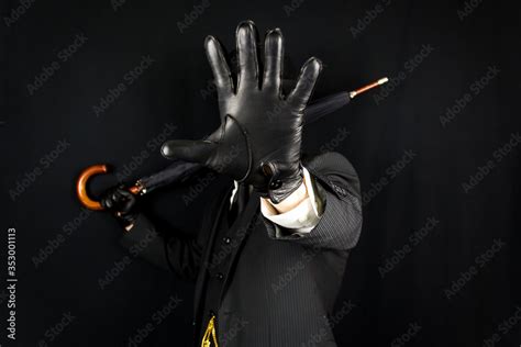 Dramatic Portrait Of Man In Dark Suit Holding Umbrella With Gloved Hand
