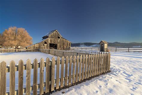 Winter Farm With Wood Fence And Barn And Snow On The Ground Stock Photo