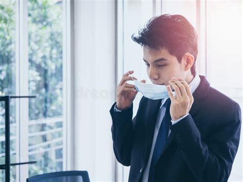 Young Asian Businessman In Suit Wearing Medical Face Mask In Office