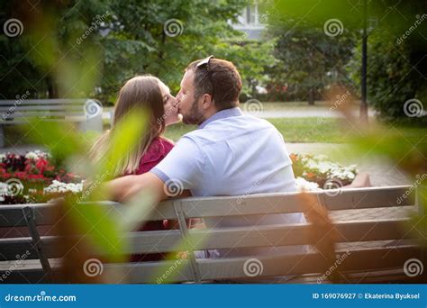 Couple In Love Is Sitting On A Bench Man And Woman Enjoy Each Other`s Conversation In The