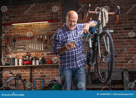 Mechanic In A Bicycle Repair Shop Using His Mobile Stock Photo Image