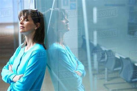 Mature Businesswoman Leaning Against Glass Wall In Office With Eyes
