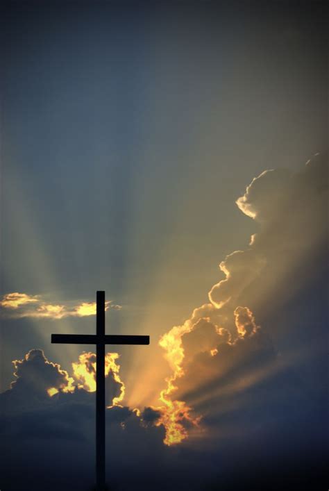 A Cross With The Sun Shining Behind It In Front Of Some Clouds And Blue Sky