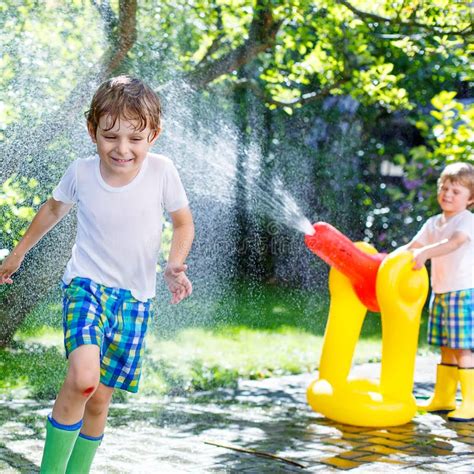 Two Little Kids Playing With Garden Hose In Summer Stock Photo Image