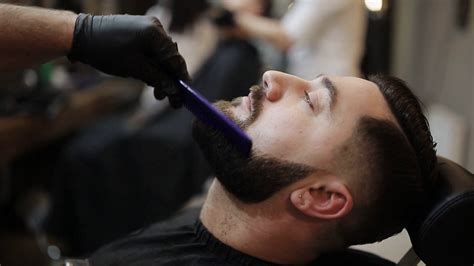 Barber Shaves The Beard Of The Client With Trimmer Stock Video Footage