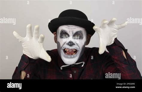 A Horrible Man In Clown Makeup Grimaces And Makes Frightening Gestures
